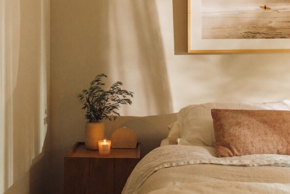 Neutral linen bedding and a wood nightstand styled with a small lamp in Camille Styles’ daughter’s bedroom.