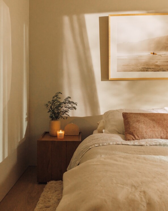 Neutral linen bedding and a wood nightstand styled with a small lamp in Camille Styles’ daughter’s bedroom.