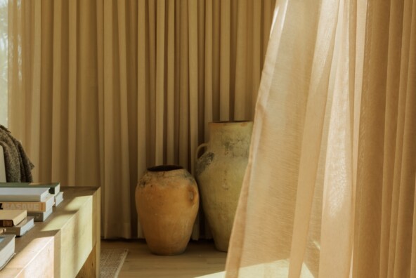 Floor-to-ceiling curtains filtering warm afternoon light in Camille Styles’ Malibu family room.