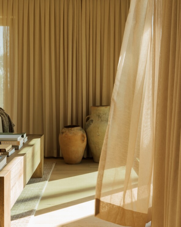 Floor-to-ceiling curtains filtering warm afternoon light in Camille Styles’ Malibu family room.