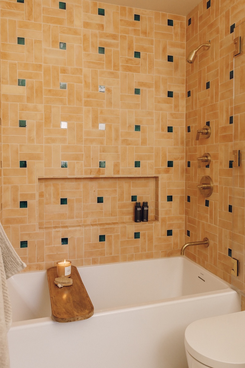 Kids’ bathroom with a white bathtub and handmade peach tile accented by small green squares.