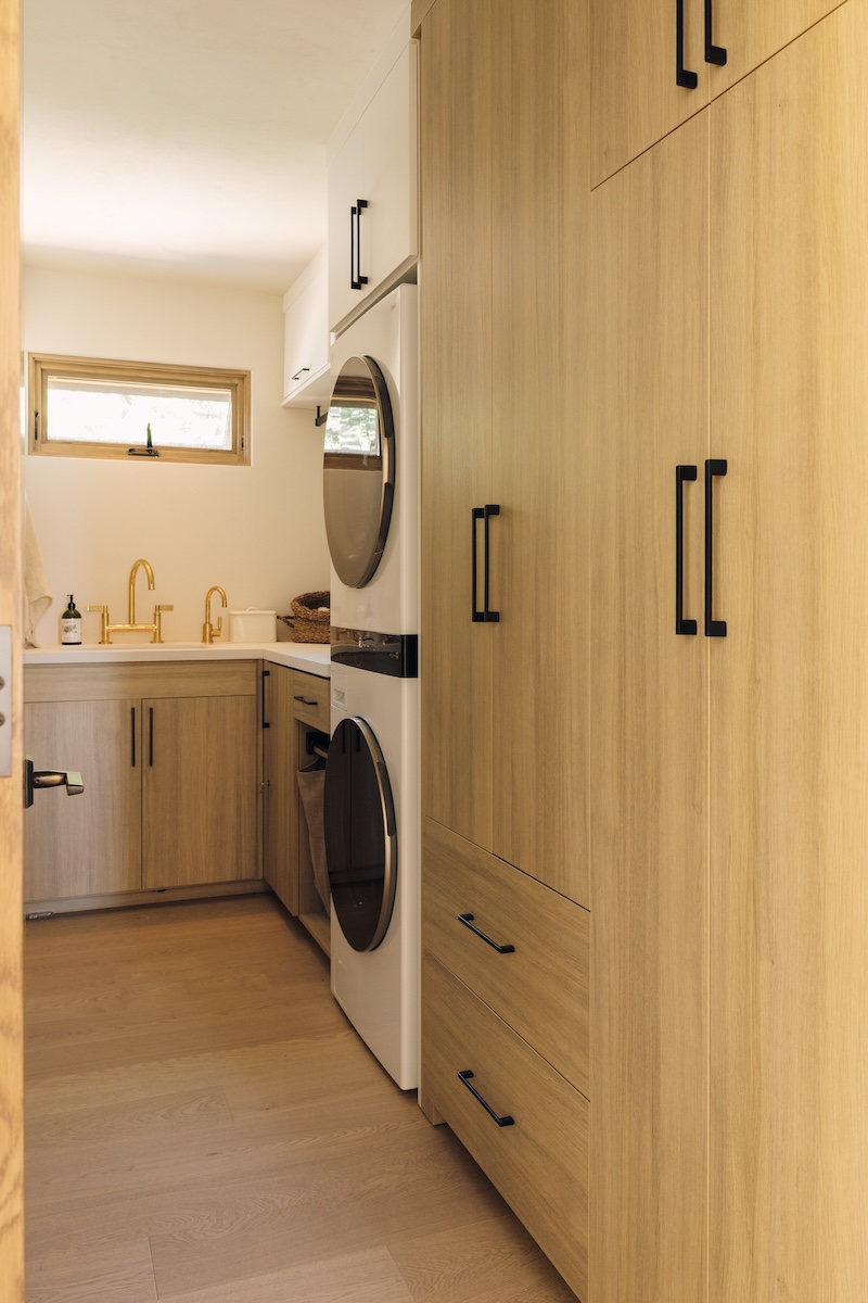 Floor-to-ceiling wood storage cabinets and laundry appliances in Camille Styles’ Malibu home.