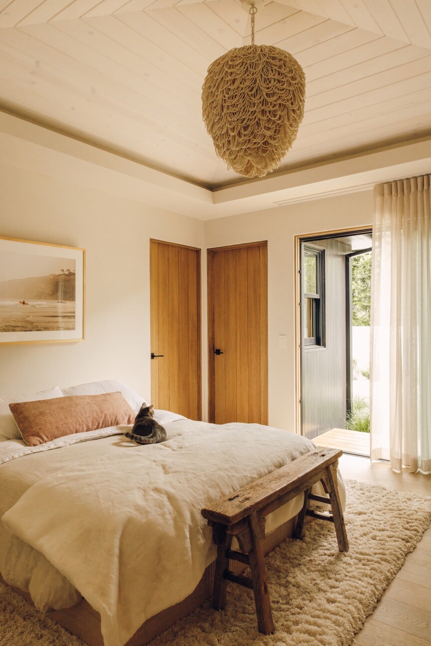 Sunlit Malibu bedroom with sheer curtains, warm wood accents, and a neutral upholstered bed.
