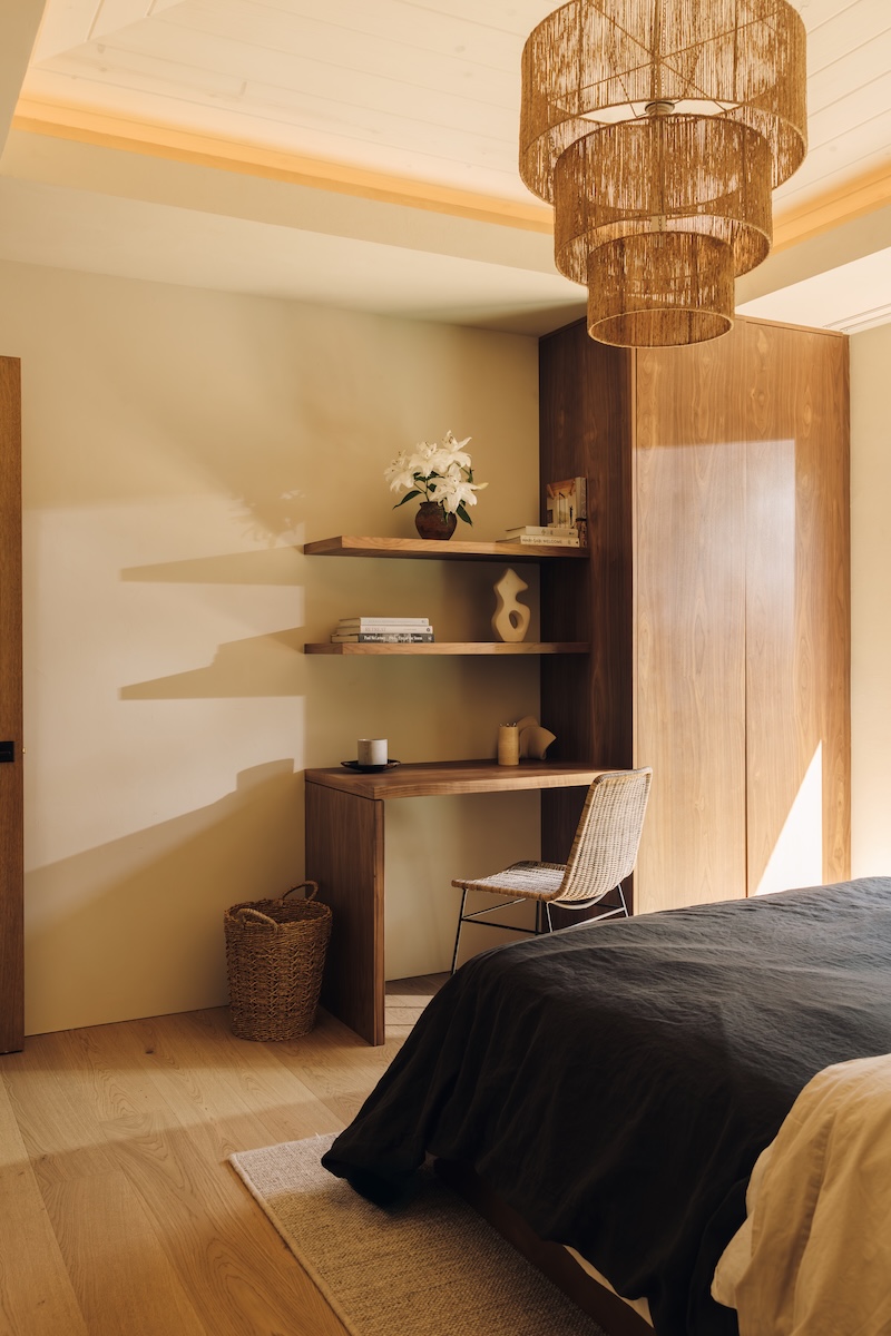 Camille Styles’ son’s bedroom with dark linen bedding, floating wood shelves, and a woven pendant light.
