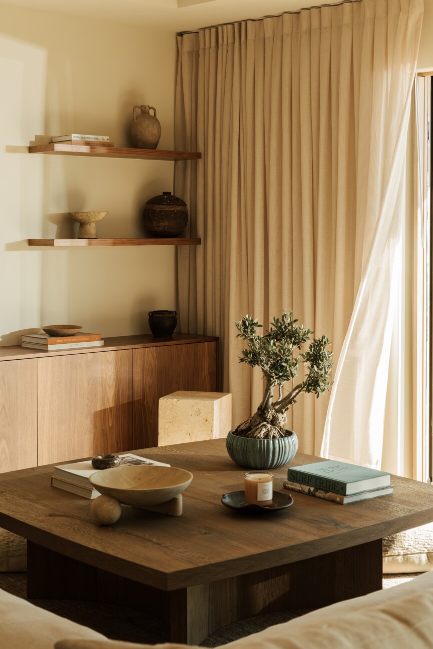 Wood coffee table styled with books, ceramics, and greenery beside the family room’s built-in cabinetry.