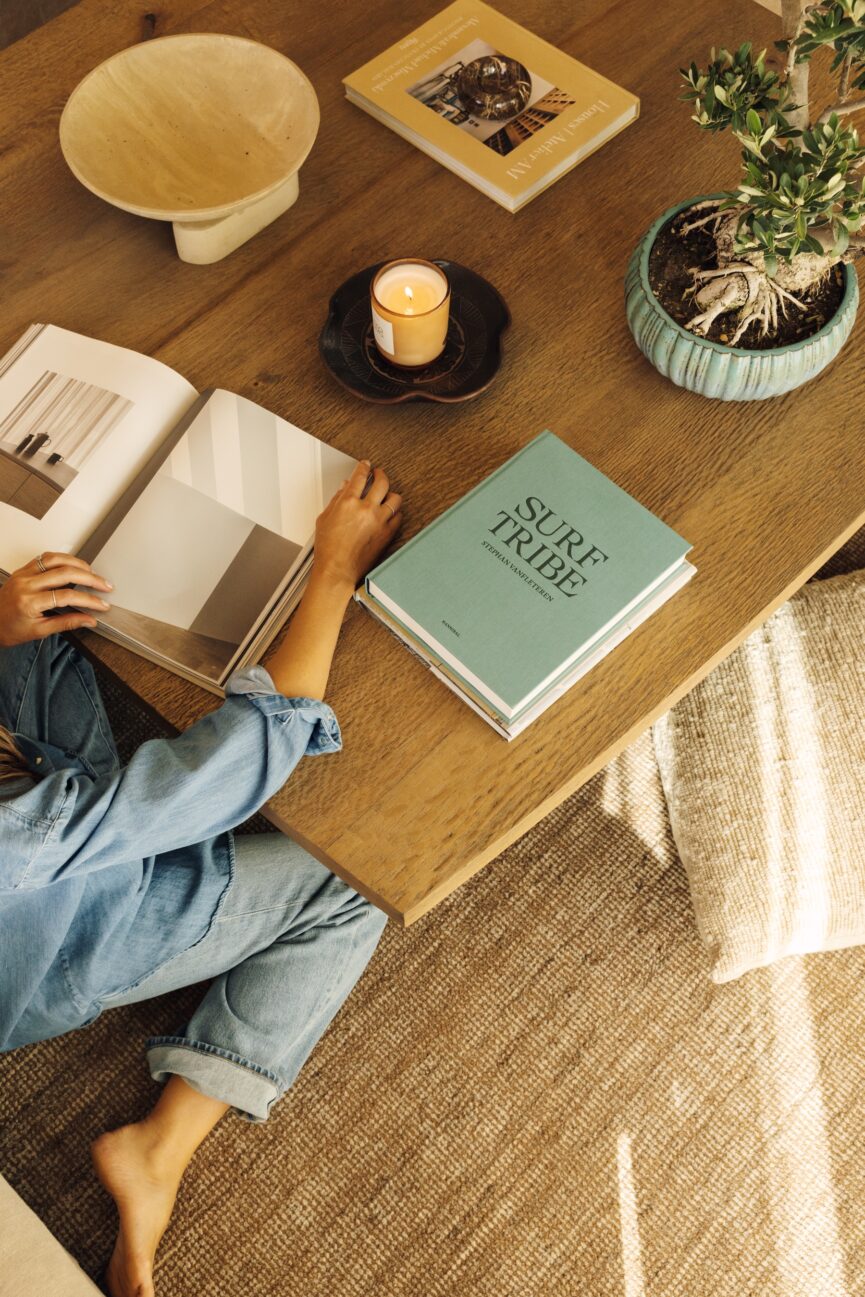 Overhead view of the family room coffee table styled with books, ceramics, a candle, and greenery.