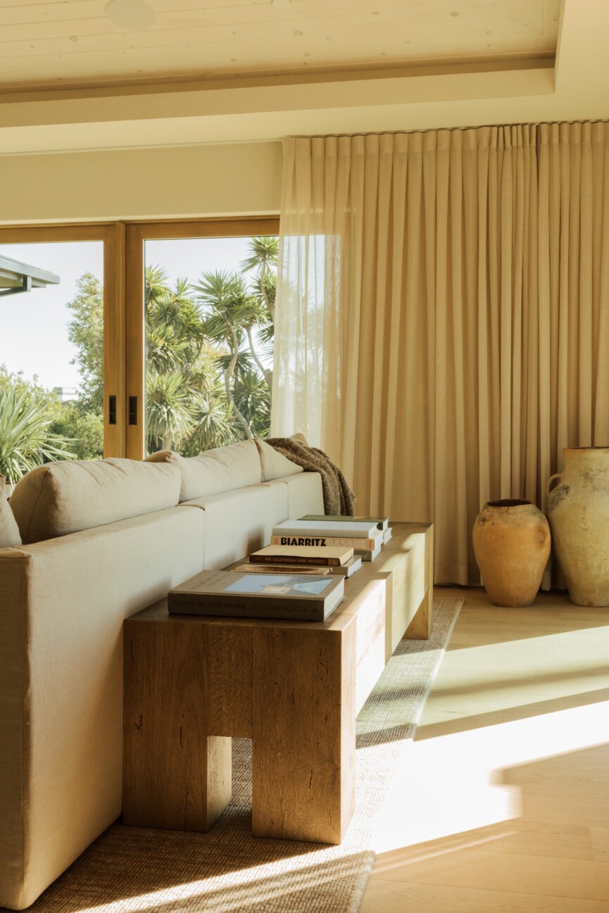 Slim wood console table behind the family room sofa, styled with books and lit by the afternoon sun.