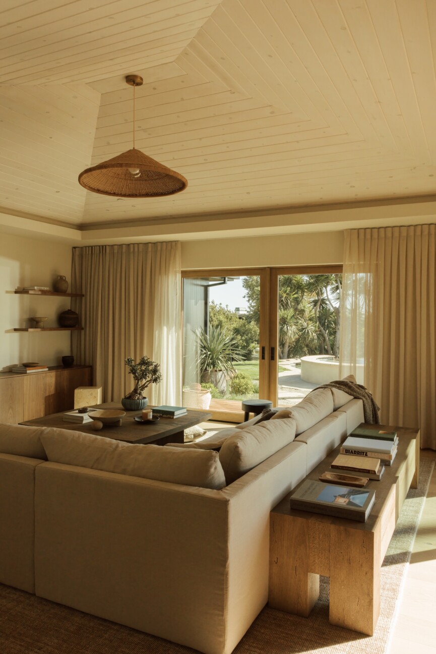 Camille Styles’ family room with a neutral sectional, Casa Zuma pendant, and doors opening to the garden.