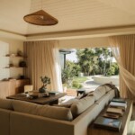 Neutral sectional and wood console in Camille Styles’ family room, framed by a Casa Zuma pendant and garden view.