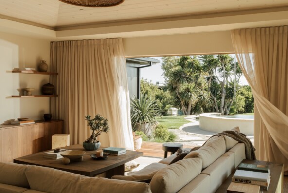 Neutral sectional and wood console in Camille Styles’ family room, framed by a Casa Zuma pendant and garden view.