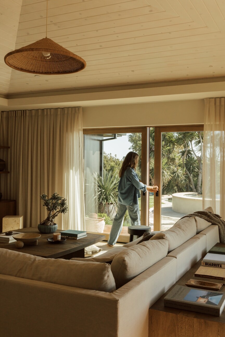 Camille Styles opens the glass doors of her Malibu family room beneath a Casa Zuma woven pendant.