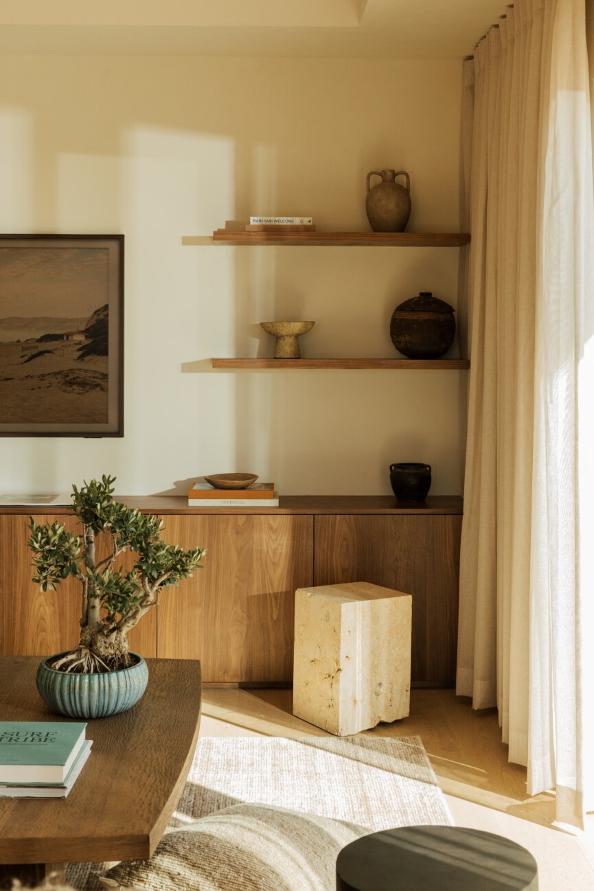 Floating wood shelves and built-in cabinetry displaying books and handmade ceramics in the Malibu family room.
