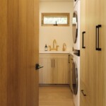 Camille Styles’ narrow Malibu laundry room with warm wood cabinetry, integrated appliances, and a utility sink.