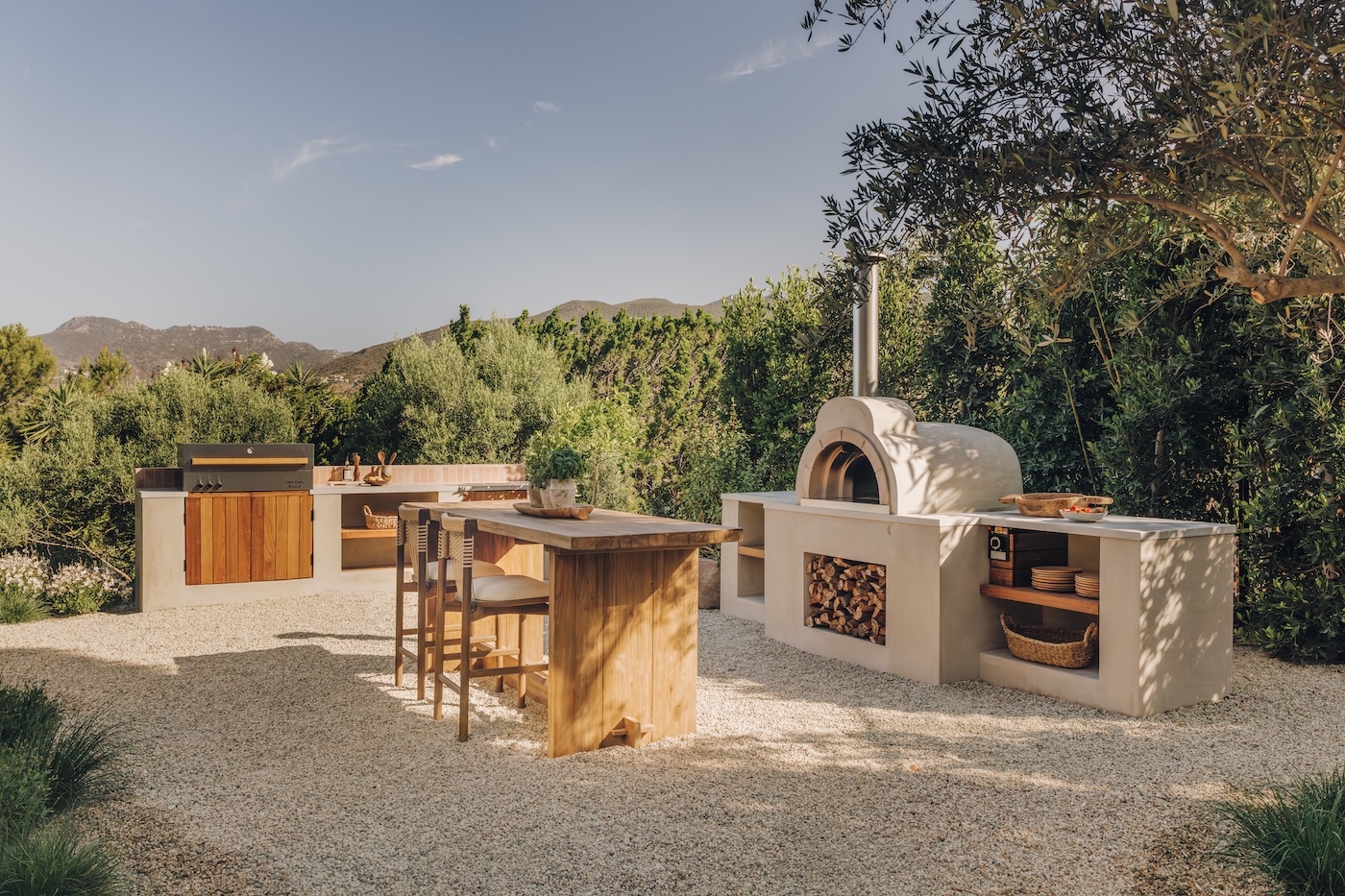 Camille Styles’ Malibu outdoor kitchen with a wood-fired pizza oven, built-in grill, and central prep island.