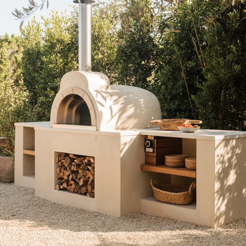 Built-in wood-fired pizza oven with open shelving and firewood storage in the Malibu outdoor kitchen.