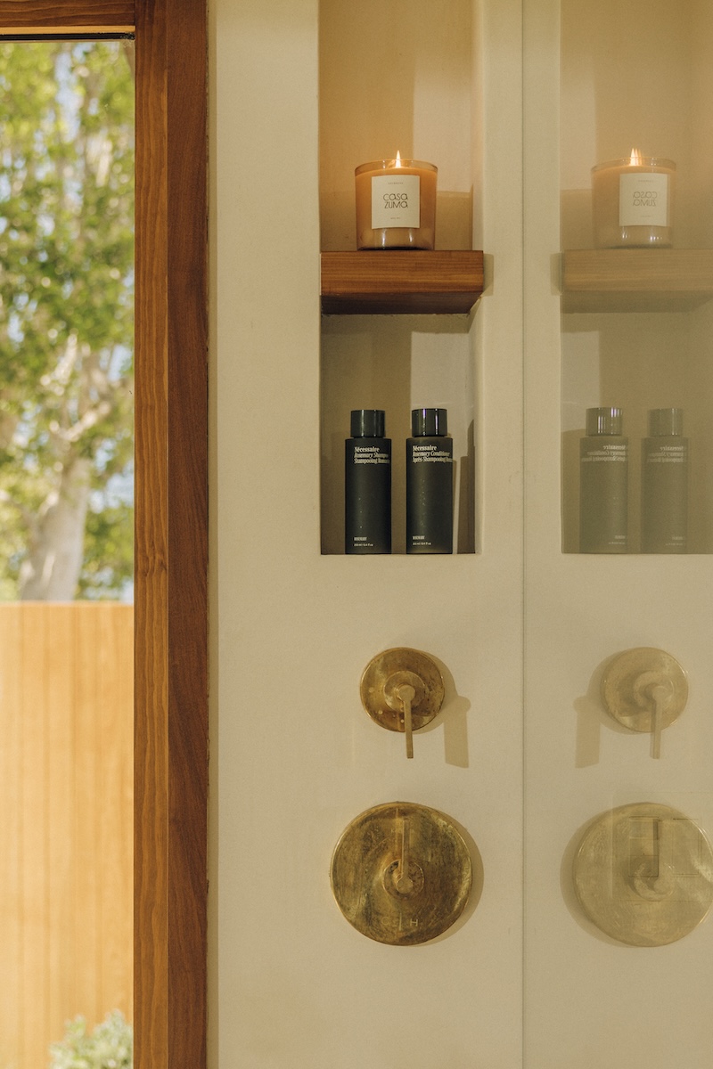 Built-in shower niche with bath products and aged brass controls in Camille Styles’ primary bathroom.