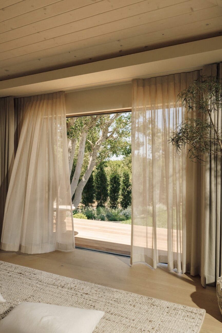 Sheer curtains moving in the breeze beside an open doorway in Camille Styles’ Malibu bedroom.